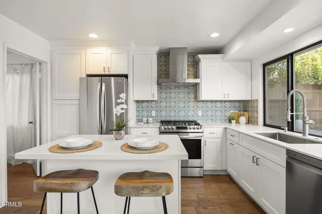 a kitchen with a refrigerator a stove a sink dishwasher with a dining table and chairs