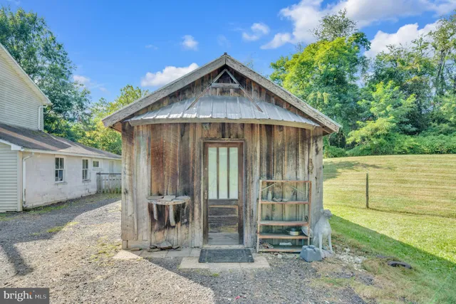 a view of a small house with wooden fence next to a yard