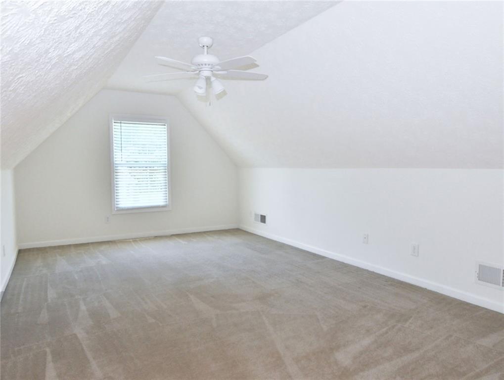 795 Sunset Ridge Lane Southeast Lawrenceville, GA 30045 - Photo 29 of 57 an empty room with a chandelier fan and windows