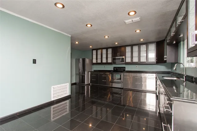 a kitchen with stainless steel appliances granite countertop a sink refrigerator and cabinets