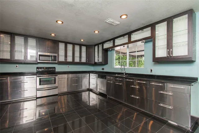 a kitchen with stainless steel appliances granite countertop a stove sink microwave and window