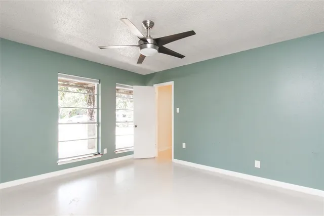 an empty room with windows and fan