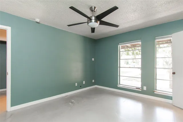 an empty room with windows and fan