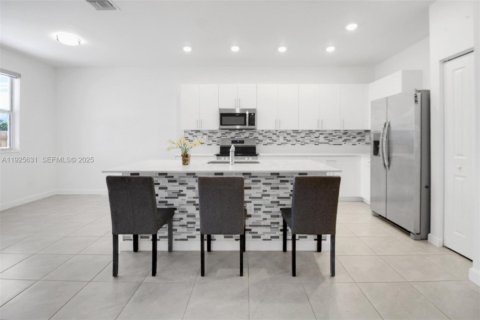 879 Southeast 26th Terrace Homestead, FL 33035 - Photo 13 of 43 a kitchen with a dining table chairs refrigerator and cabinets