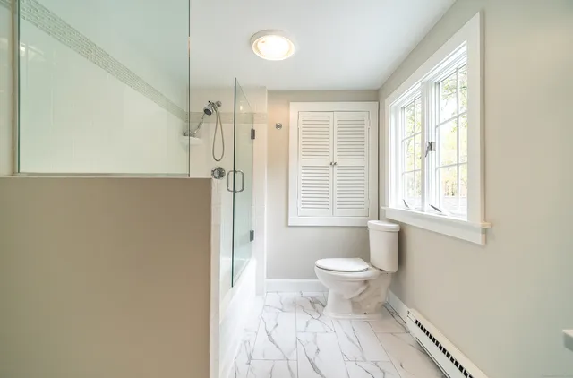 a backyard of a house with large trees and brick wall