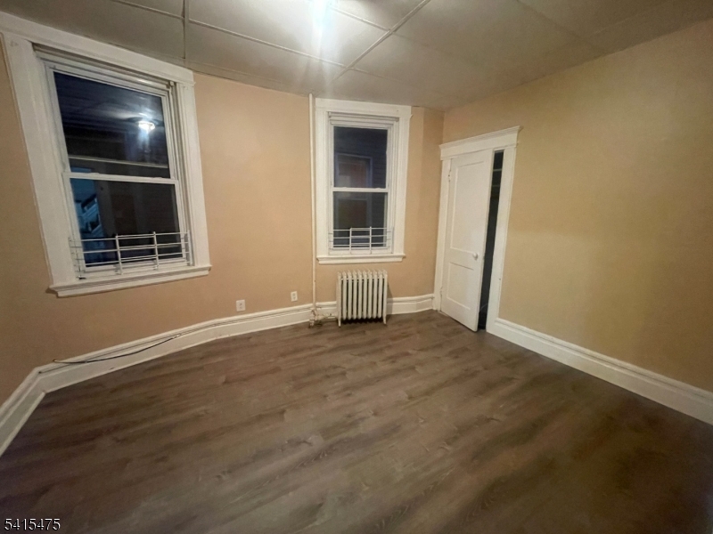 43 Mapes Avenue, Unit 2L Newark, NJ 07112 - Photo 5 of 7 an empty room with wooden floor and windows