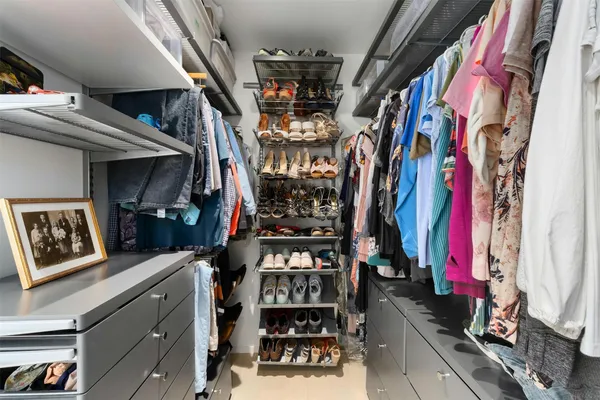 a view of walk in closet with clothes and shoes