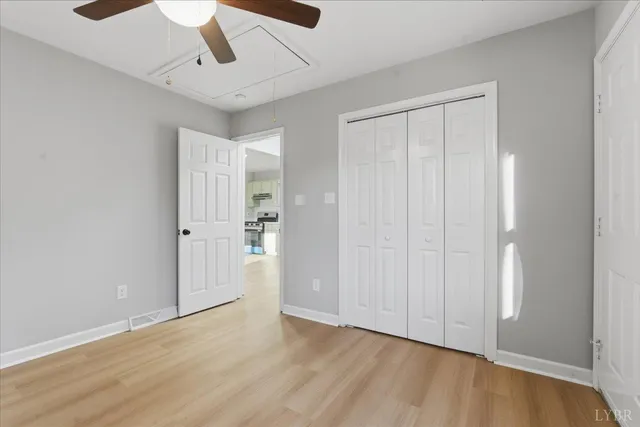 an empty room with wooden floor ceiling fan and windows