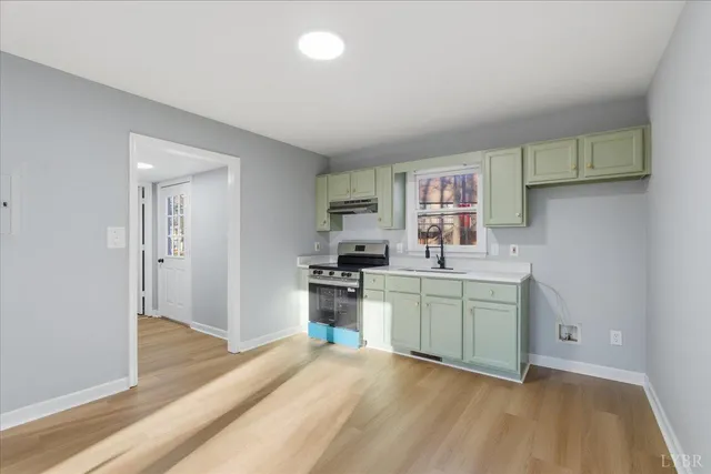 a view of kitchen and empty room with wooden floor