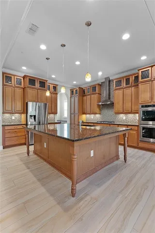 a large kitchen with stainless steel appliances a large counter top a refrigerator and cabinets