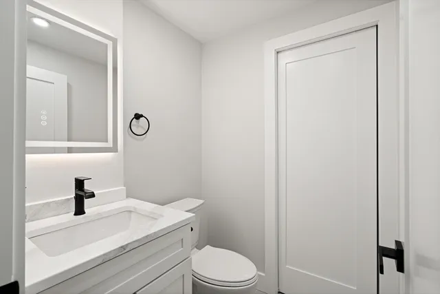 a bathroom with a toilet sink vanity and mirror