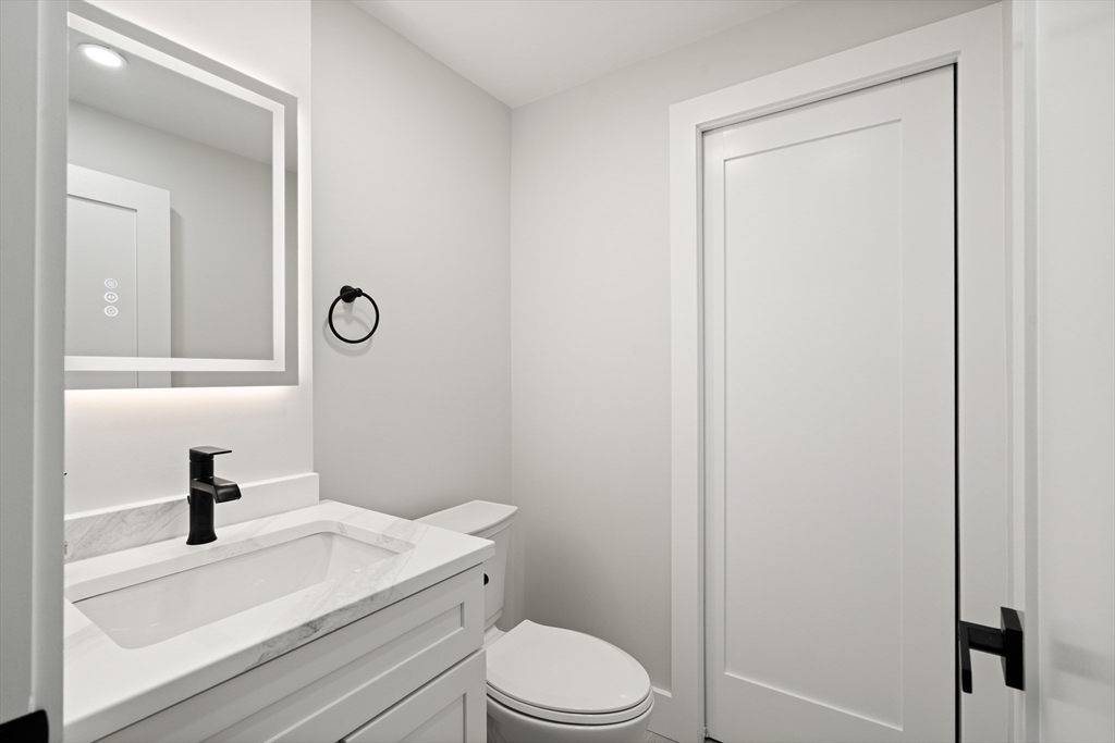 35 Dewey Street, Unit 35 Boston, MA 02125 - Photo 28 of 30 a bathroom with a toilet sink vanity and mirror