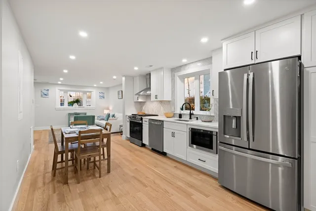 a kitchen with stainless steel appliances a refrigerator a stove a dining table and chairs