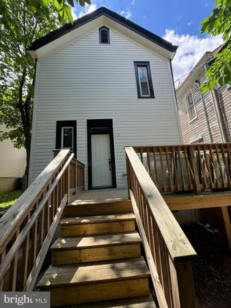 a view of wooden staircase with railing and white walls