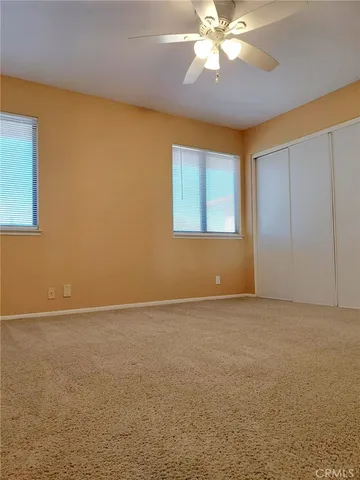an empty room with windows and fan
