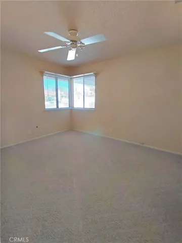 an empty room with a ceiling fan and window