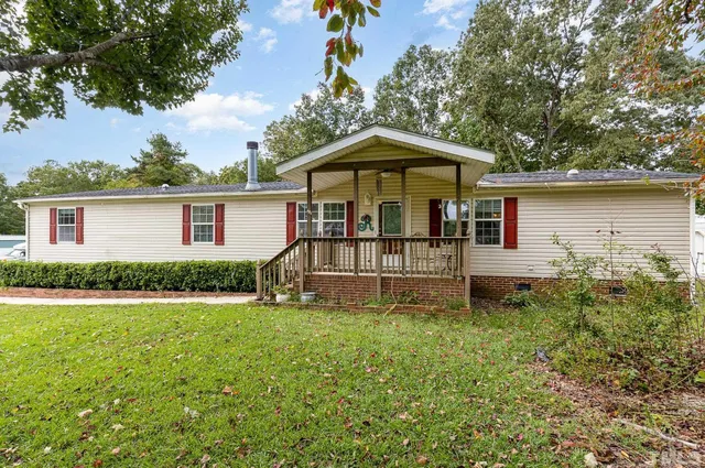 a white house that has a small yard and large trees
