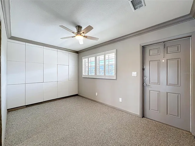an empty room with windows and fan