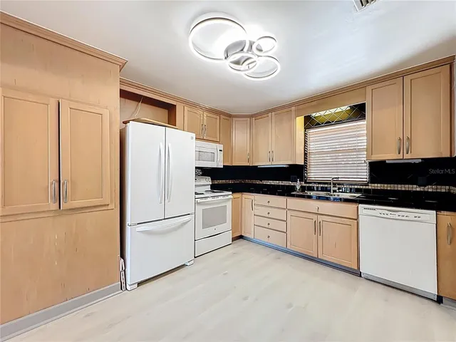 a kitchen with granite countertop white cabinets and white appliances