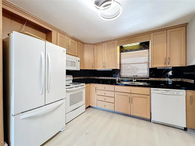 a kitchen with granite countertop white cabinets and white appliances