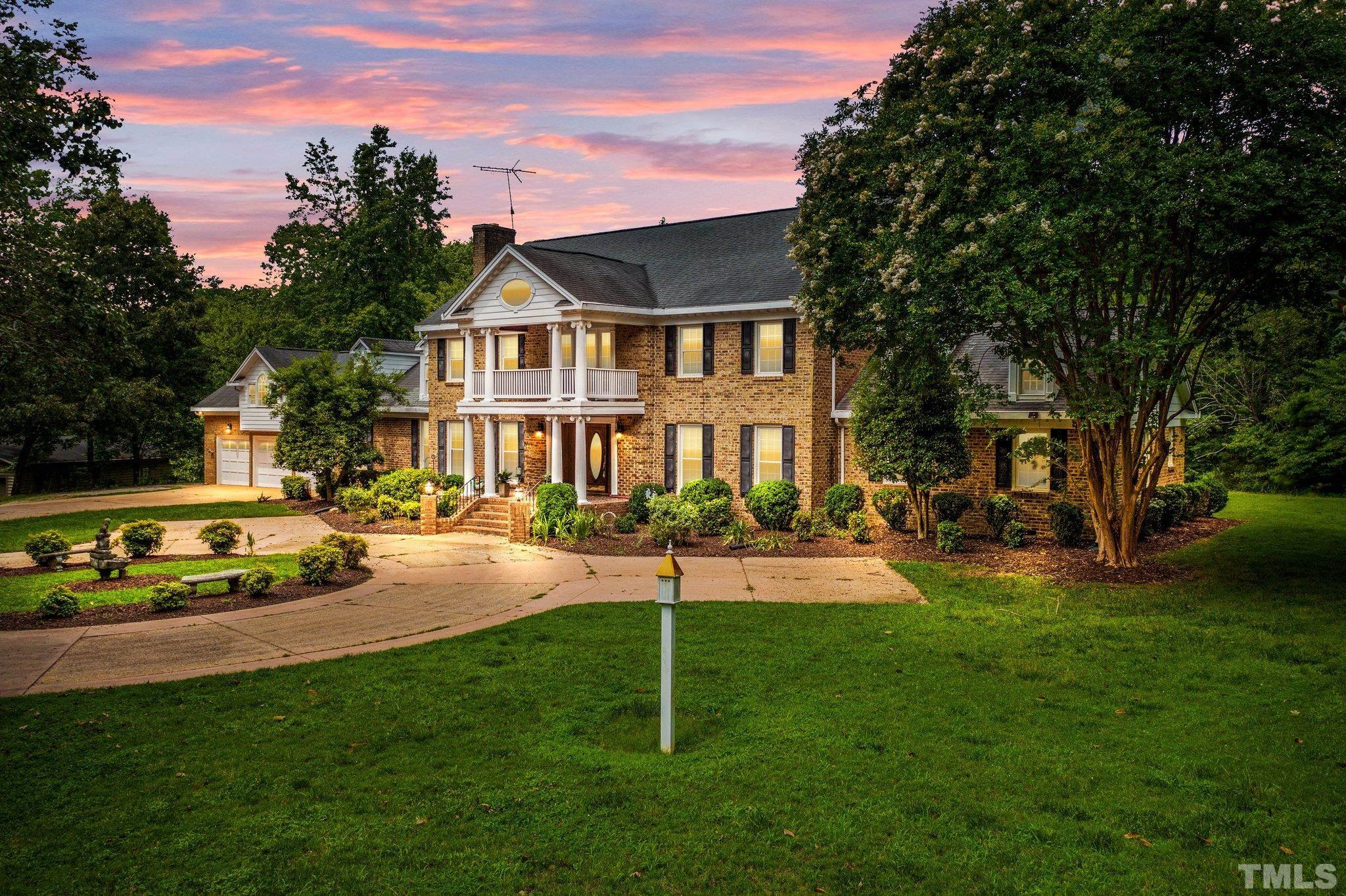 a view of a house with a big yard plants and large trees