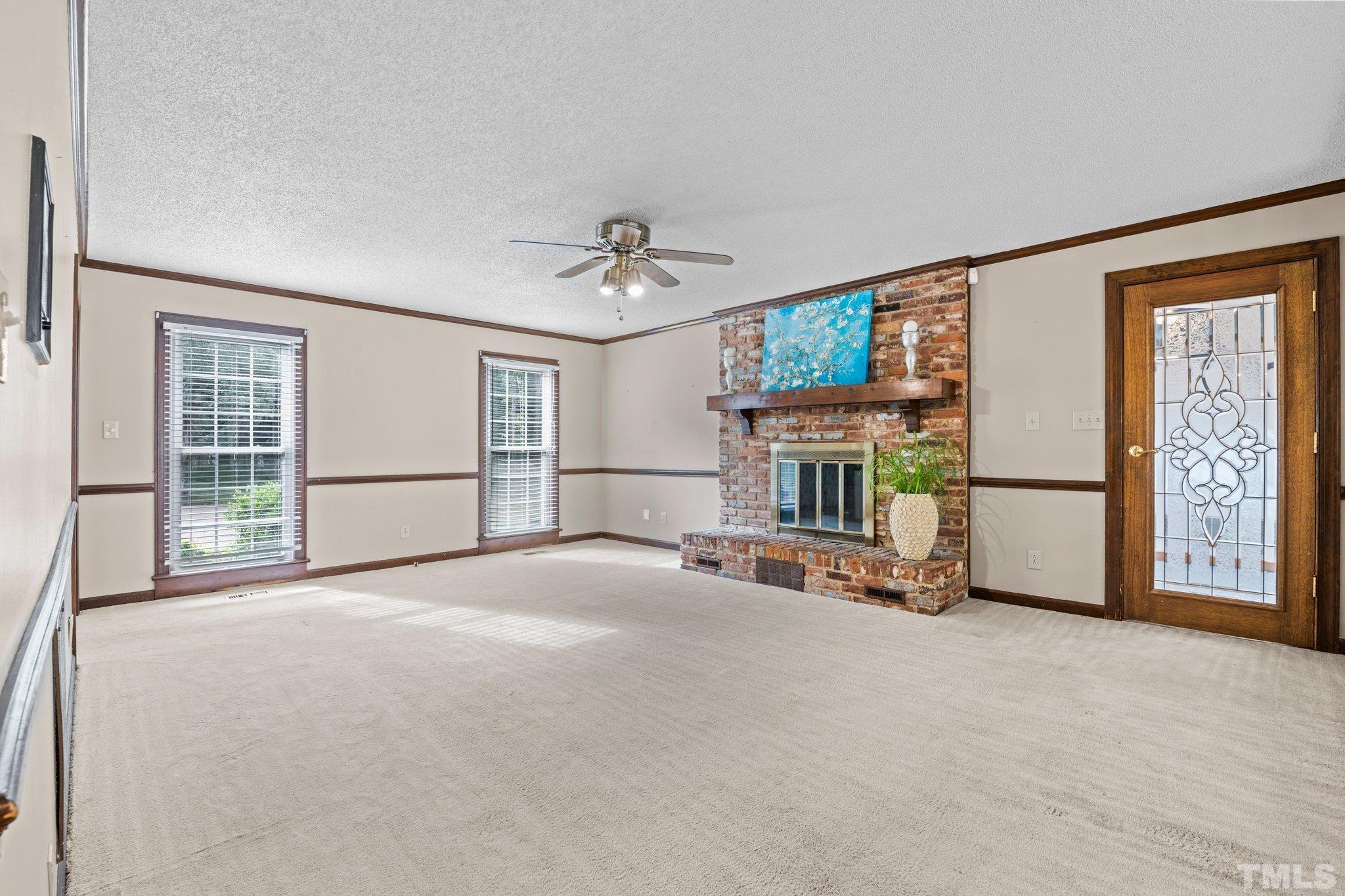 7525 South Tanglewild Drive Raleigh, NC 27613 - Photo 14 of 50 a view of an empty room with a fireplace and a window
