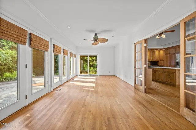 a view of a kitchen with wooden floor a ceiling fan and windows