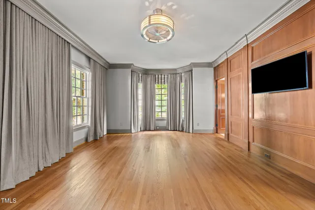 a view of an empty room with a window and wooden floor