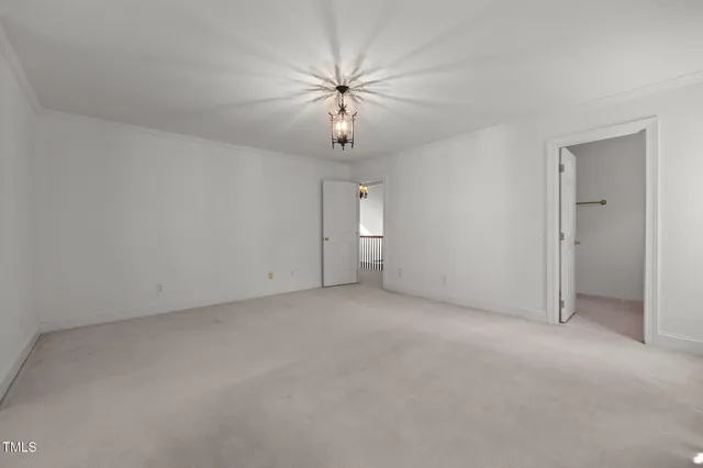 an empty room with chandelier fan and windows