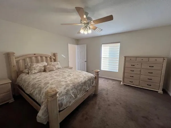 a spacious bedroom with a bed and a ceiling fan