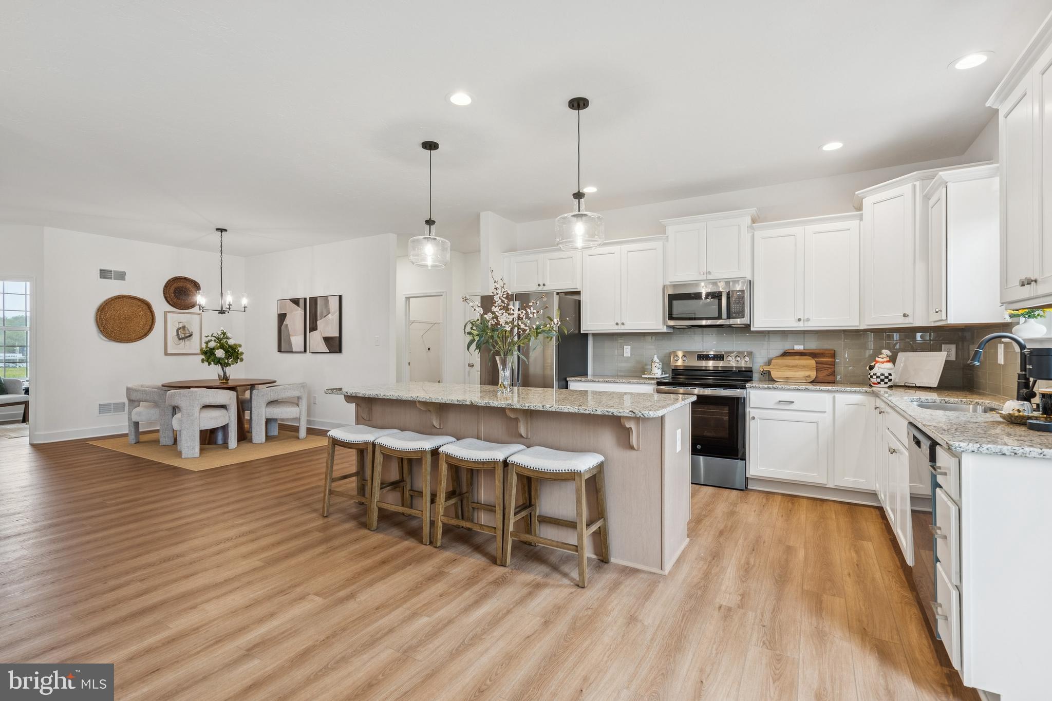 150 Piedmont Way, Unit 101 Hanover, PA 17331 - Photo 6 of 40 a kitchen with stainless steel appliances granite countertop a stove top oven a sink dishwasher white cabinets and a chairs with wooden floor