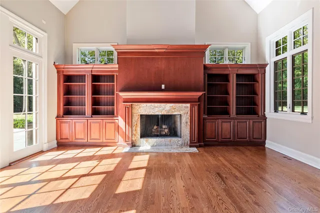 a view of an empty room with wooden floor fireplace and windows