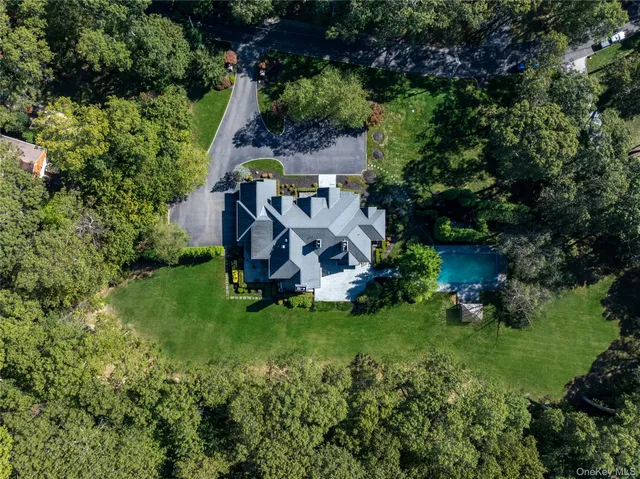 an aerial view of residential house with outdoor space and trees all around