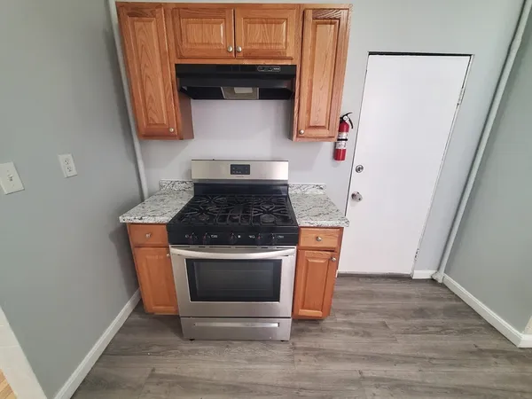 a kitchen with granite countertop wood cabinets and a stove top oven