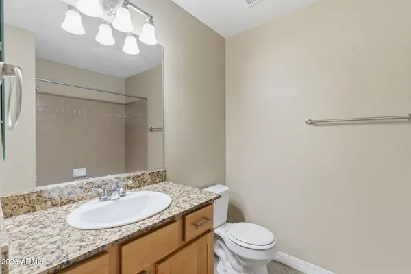 a bathroom with a granite countertop sink a toilet and a mirror