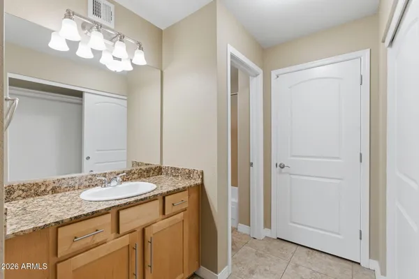 a bathroom with a granite countertop sink a light fixture and a mirror