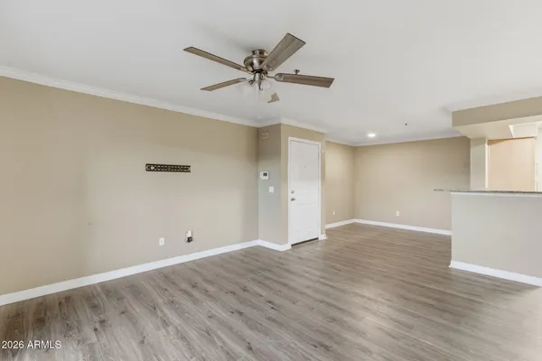 a view of an empty room with wooden floor and a ceiling fan
