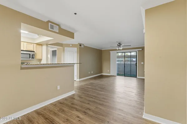 a view of an empty room with wooden floor and a window