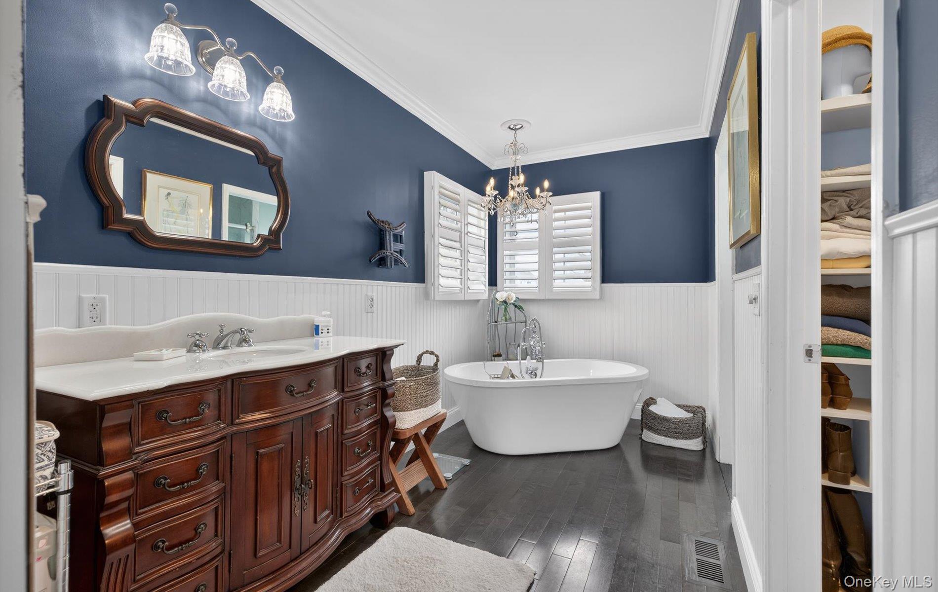 108 Awixa Avenue Bay Shore, NY 11706 - Photo 18 of 47 Bathroom featuring vanity, dark wood-style floors, ornamental molding, a freestanding bath, and a wainscoted wall