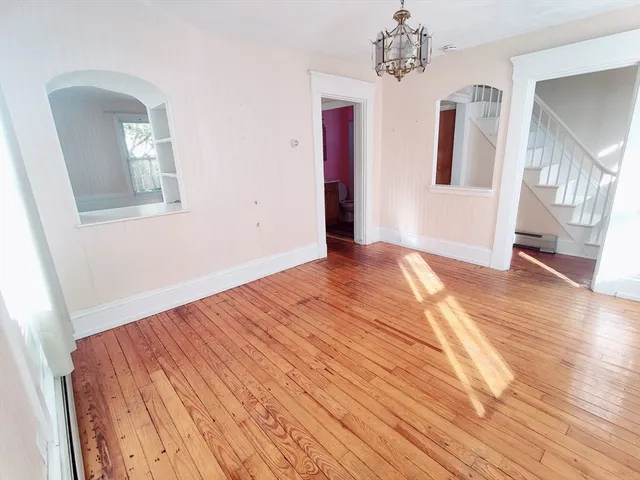 a view of an empty room with window and wooden floor