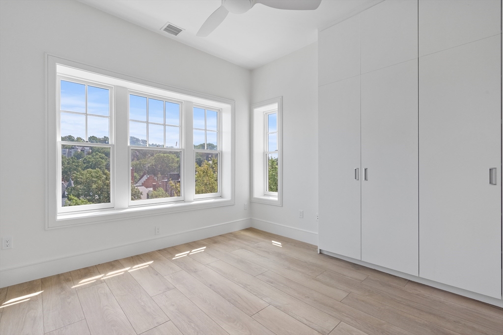 1580 Beacon Street, Unit 100 Brookline, MA 02446 - Photo 6 of 17 an empty room with wooden floor and windows