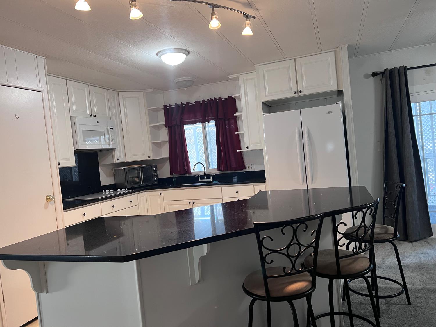 3913 Waimea Lane Modesto, CA 95355 - Photo 13 of 32 a kitchen with stainless steel appliances a sink a stove a refrigerator cabinets and a dining table