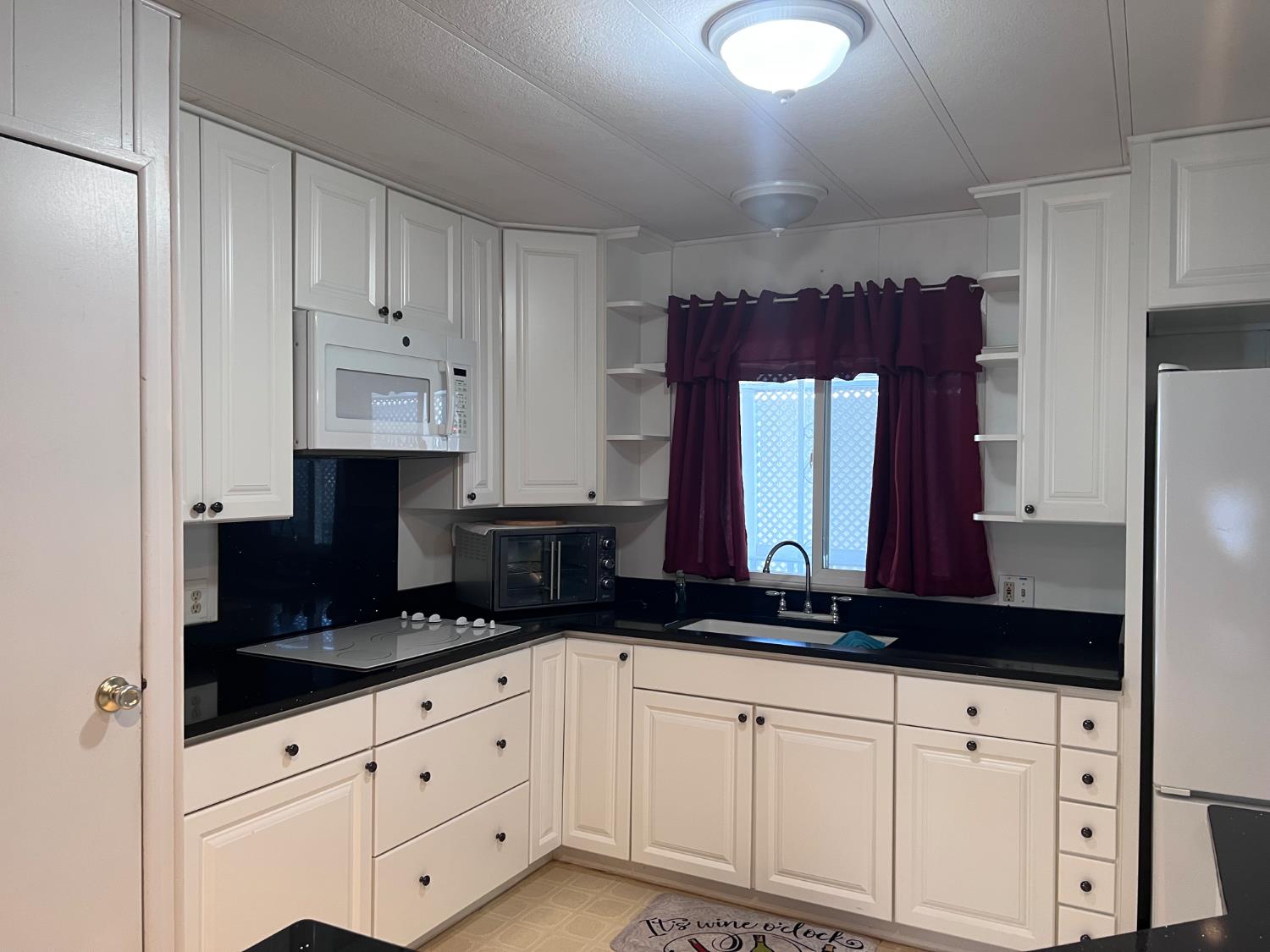 3913 Waimea Lane Modesto, CA 95355 - Photo 14 of 32 a kitchen with granite countertop white cabinets and black appliances