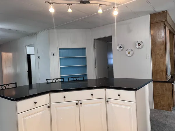 a kitchen with kitchen island stainless steel appliances a table chairs sink and cabinets