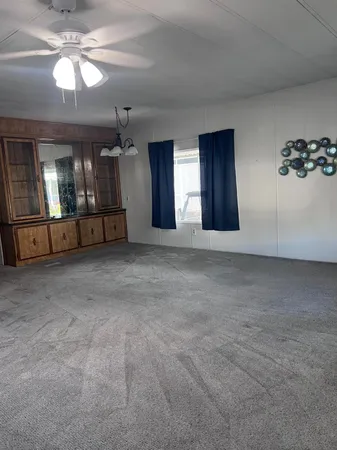 a view of an empty room with chandelier and glass door