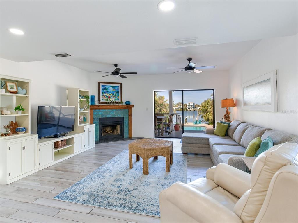 410 140th Avenue East Madeira Beach, FL 33708 - Photo 18 of 77 a living room with furniture a fireplace and a flat screen tv