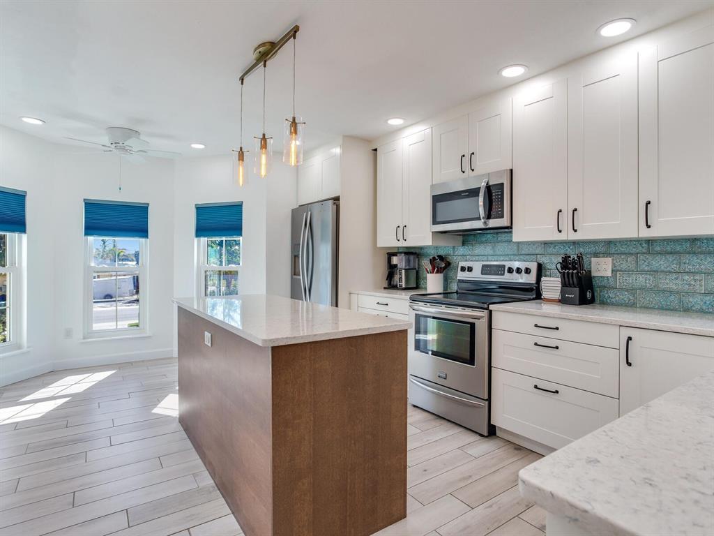 410 140th Avenue East Madeira Beach, FL 33708 - Photo 25 of 77 a kitchen with stainless steel appliances kitchen island granite countertop a stove a sink and a refrigerator