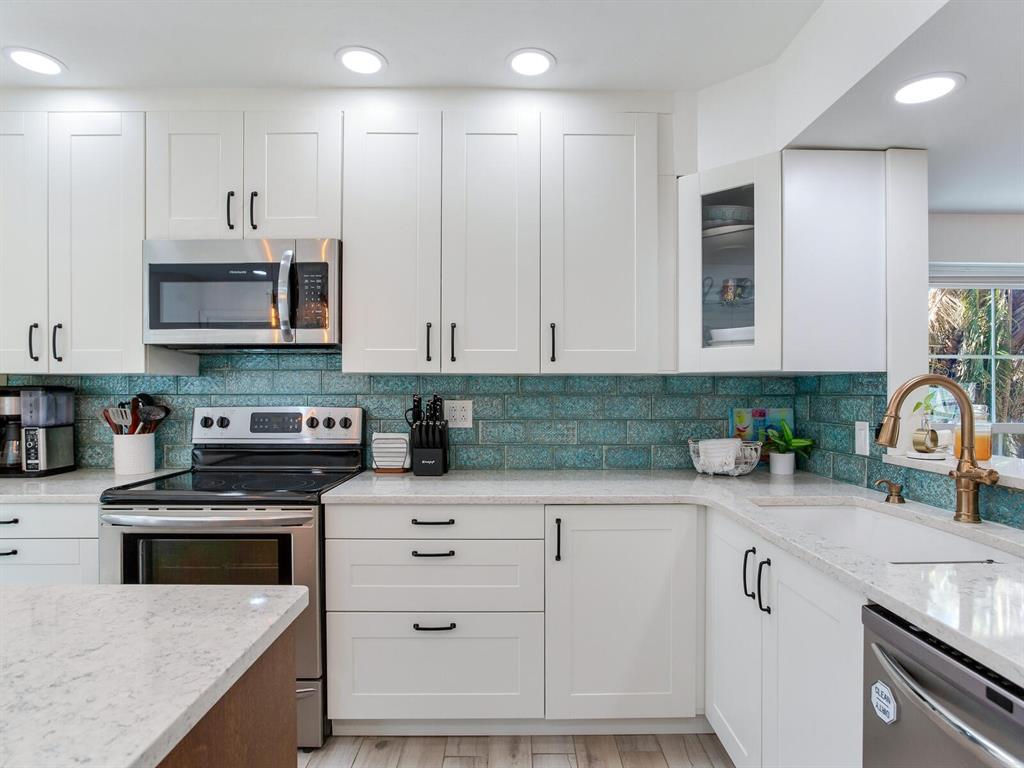 410 140th Avenue East Madeira Beach, FL 33708 - Photo 26 of 77 a kitchen with granite countertop white cabinets stainless steel appliances and a sink
