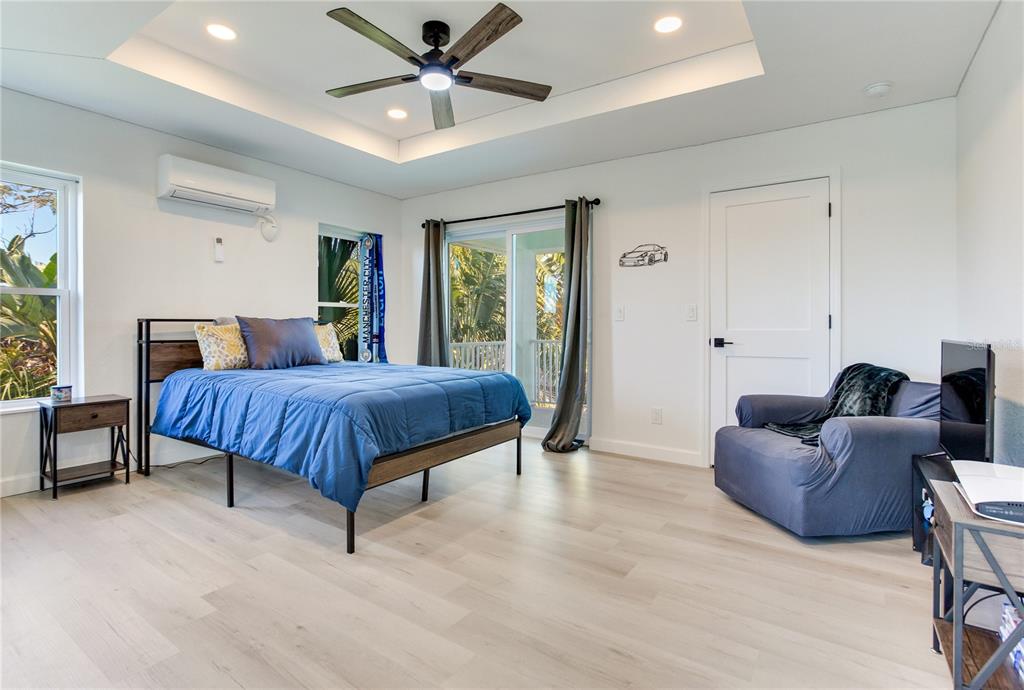 410 140th Avenue East Madeira Beach, FL 33708 - Photo 57 of 77 a spacious bedroom with a bed a couch and a chandelier