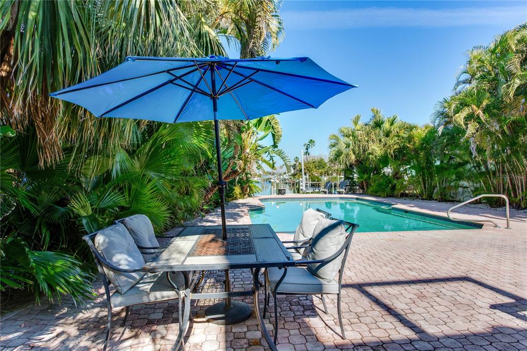 410 140th Avenue East Madeira Beach, FL 33708 - Photo 68 of 77 a patio with a table and chairs under an umbrella